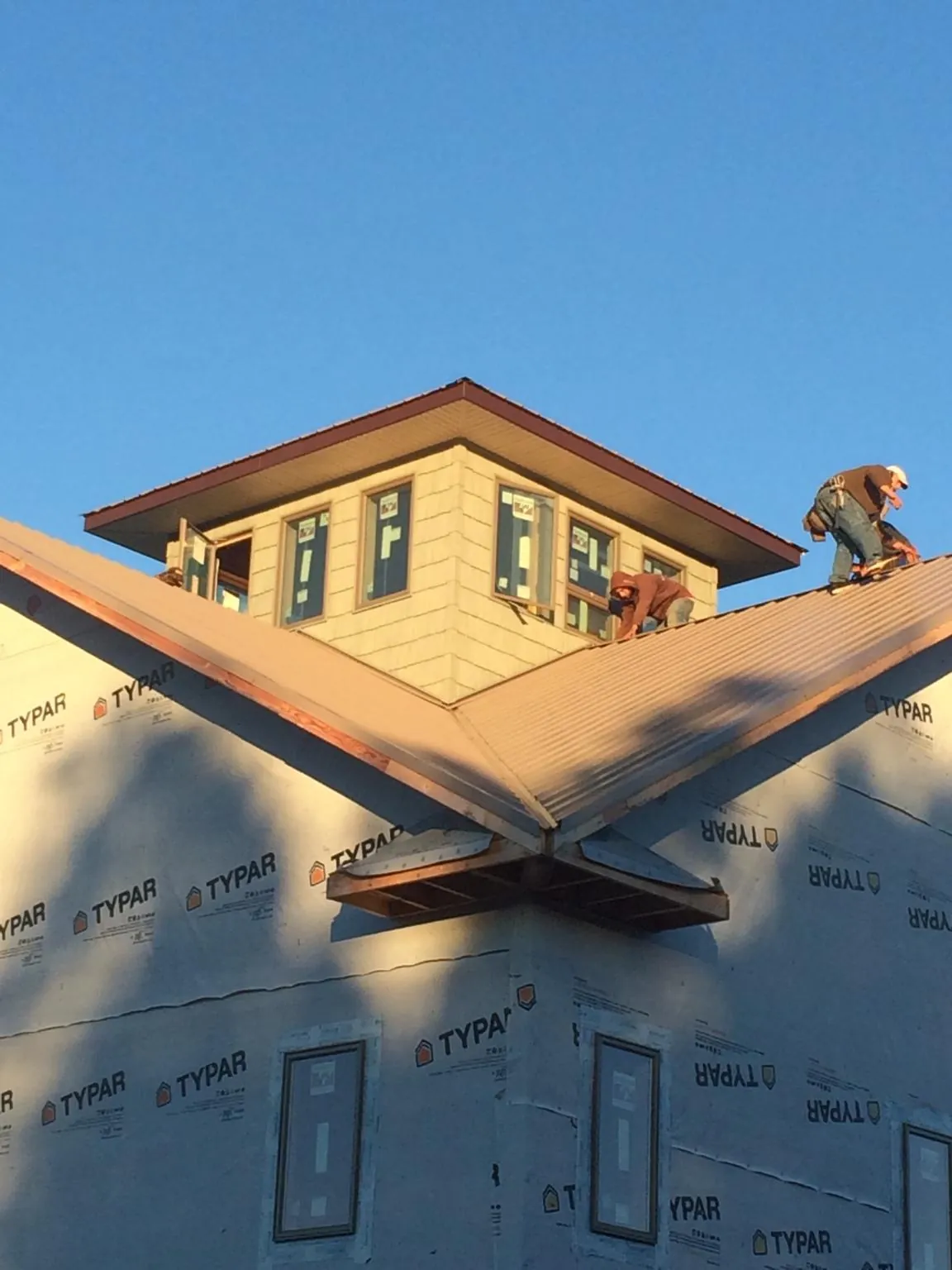 Roofers working around a rooftop cupola on a new metal roof at sunset — Roof Waterproofing in Fremont by Roofing Brothers